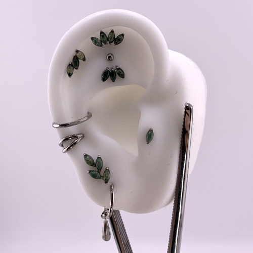 Agat mszysty - gałązka - tytanowy labret ozdobny. Imitacja naturalnego kamienia Moss Agate. Kompozycja na sztucznym uchu, dużo kolczyków. Piercing ucha helix flat lobe tragus conch upper lobe. roślinny motyw roślina roślinka